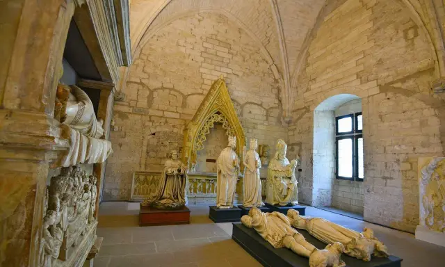Intérieur du Palais des Papes à Avignon : gisants, statues royales et religieuses sous des voûtes de pierre.