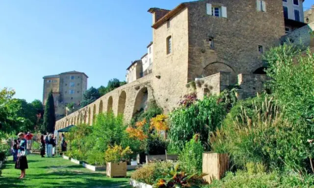 Jardin luxuriant devant le **château de Lauris**, avec ses murs de pierre et ses arches médiévales.