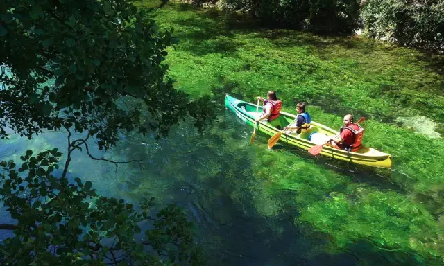 Trois personnes en canoë sur la Durance, profitant d'une baignade rafraîchissante dans des eaux turquoise et verdoyantes.