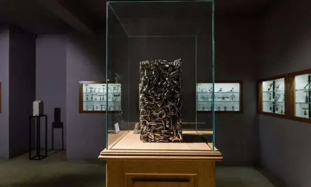 Sculpture en tire-bouchons dans une vitrine au musée du tire bouchon. Des vitrines murales exposent d'autres tire-bouchons anciens.