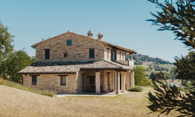 Un mas en pierre typique du sud de la France, niché dans des collines verdoyantes sous un ciel bleu éclatant.