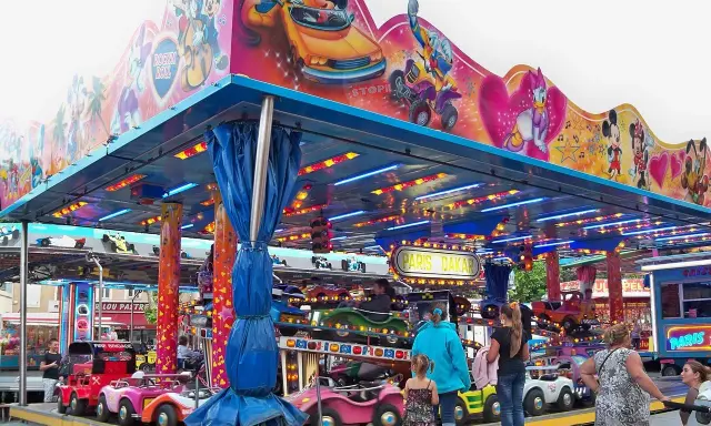 Attraction for children with cars, decorated with Mickey Mouse and friends. A sign says "Paris Dakar".