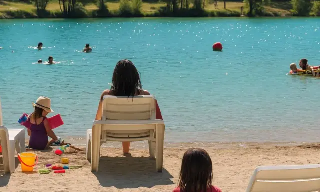 Journée baignade à L'Isle-sur-la-Sorgue. Des enfants jouent dans l'eau turquoise, d'autres sur le sable. Une mère surveille, profitant du soleil.