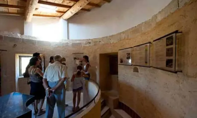 Visite du moulin de Salignan, un groupe découvre les panneaux d'exposition dans l'espace circulaire aux murs de pierre.