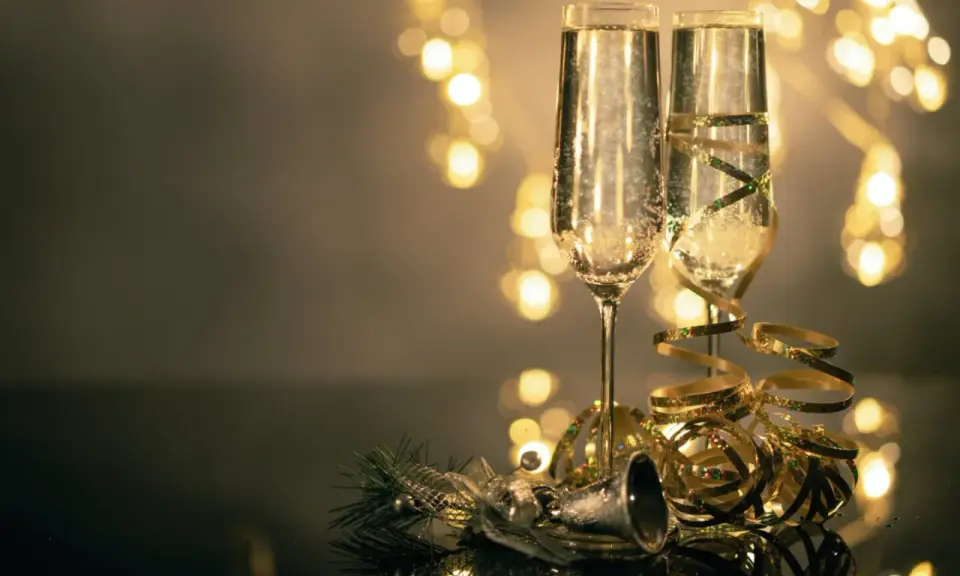 Deux flûtes de champagne pétillant, décorées de rubans dorés, prêtes pour le nouvel an à Avignon. Lumières festives en arrière-plan.