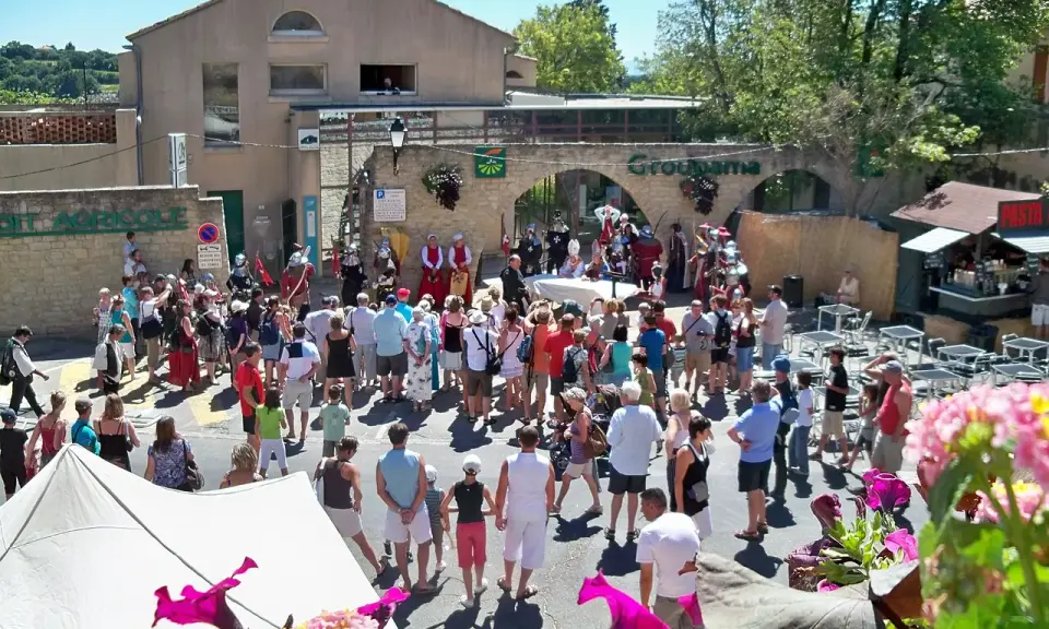 Foule en costume d'époque lors de la fête de la veraison, avec des musiciens et des stands.
