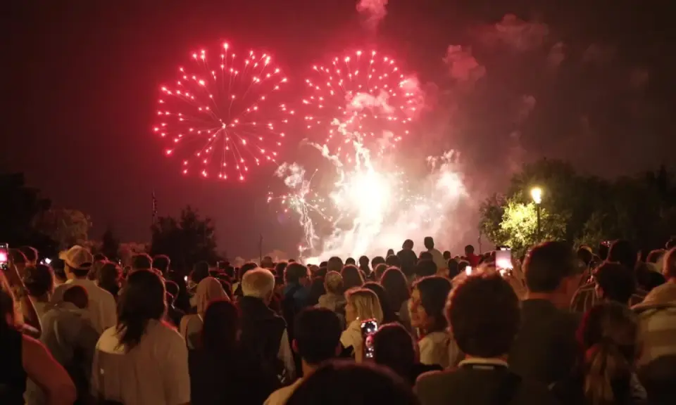 Foule admirant un magnifique feu d'artifice rouge au-dessus de la nuit, un spectacle mémorable à Lourmarin.