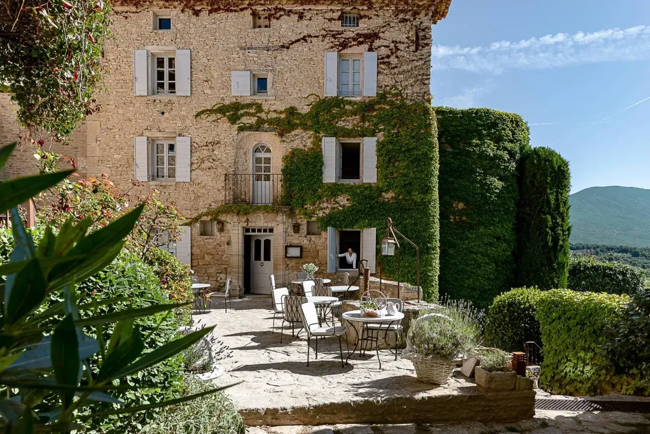 Terrasse ensoleillée d'un mas en pierre, typique de la Provence. Un cheval blanc pourrait galoper au loin, dans ce paysage bucolique.
