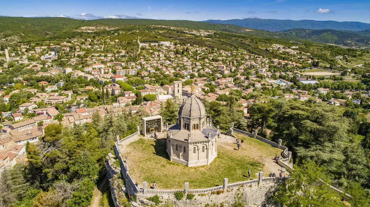 Vue aérienne de la citadelle de Forcalquier, avec son dôme imposant et le village provençal s'étendant à flanc de colline.
