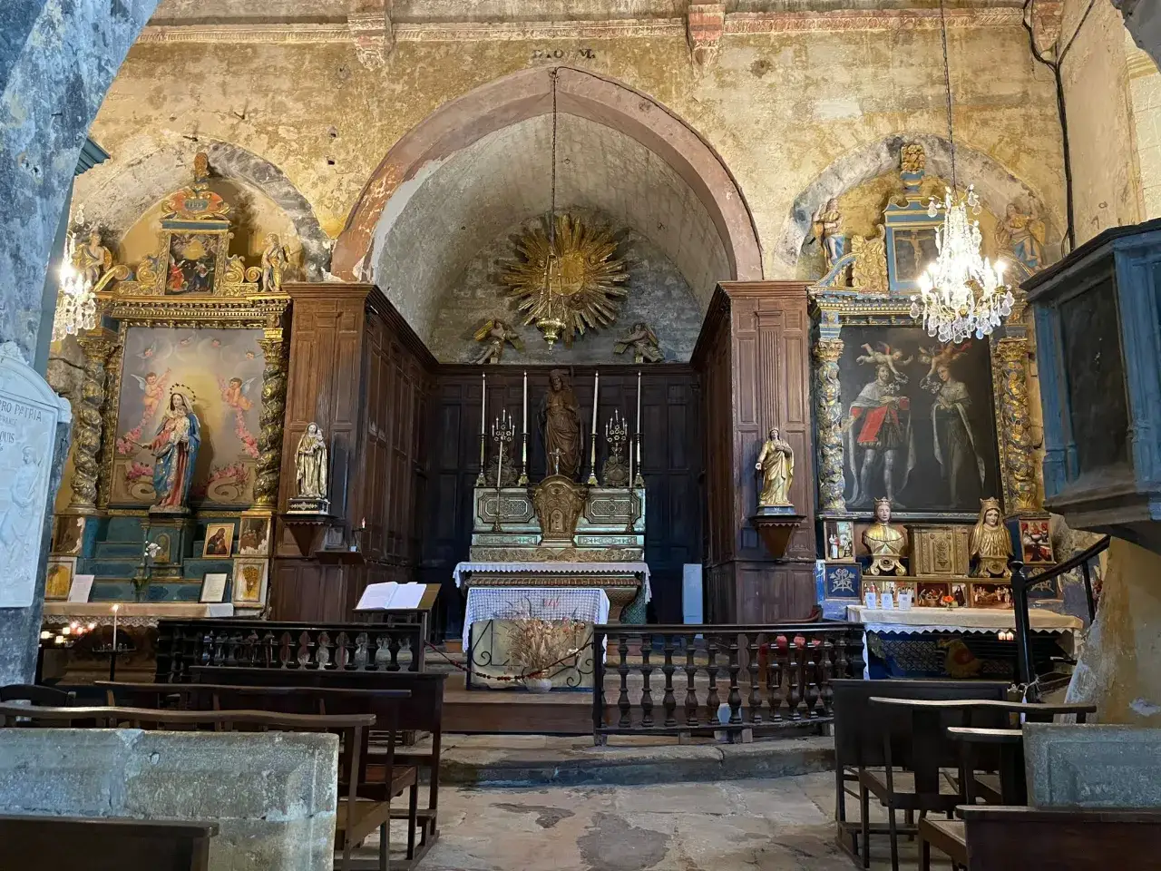 Int&eacute;rieur d'une &eacute;glise &agrave; Joucas, France, avec un autel orn&eacute;, des peintures et des statues.