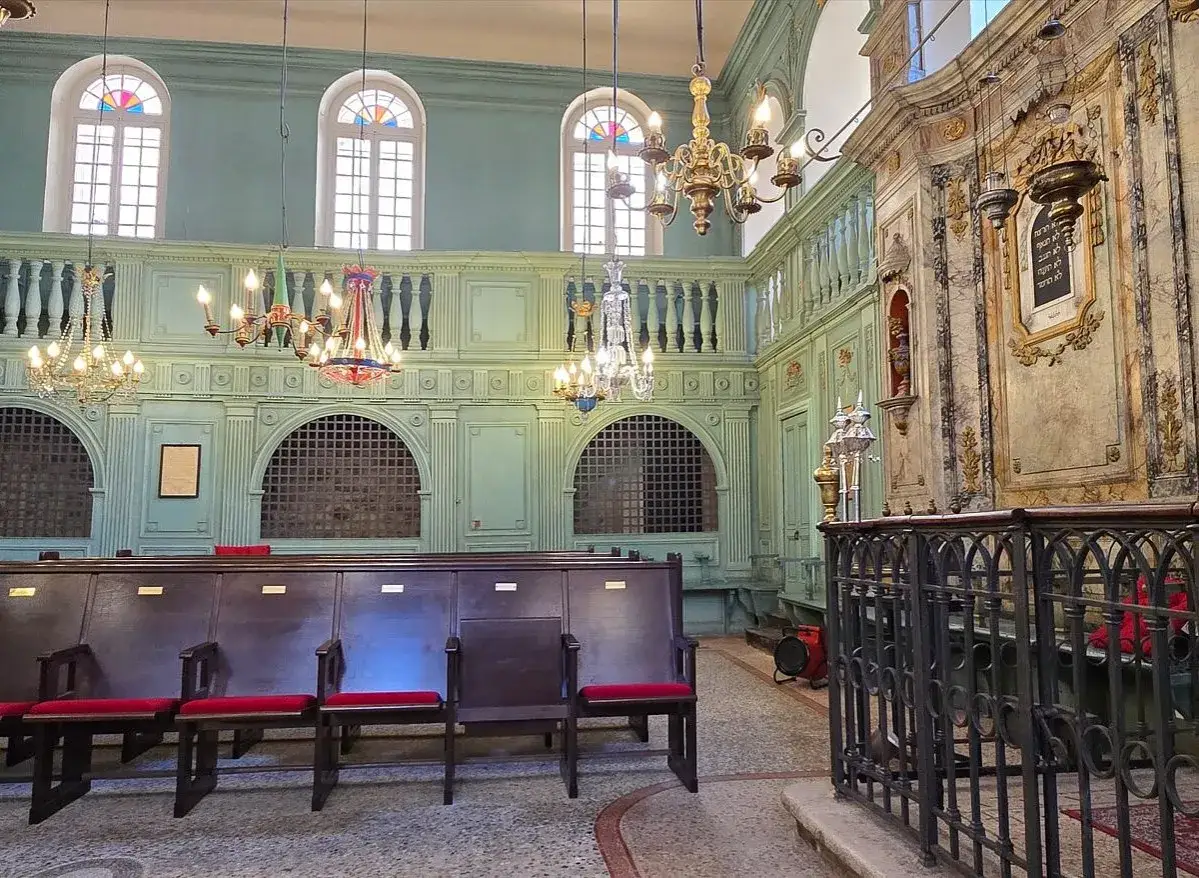 Int&eacute;rieur d'une synagogue orn&eacute;e, avec des bancs en bois, des lustres anciens et des fen&ecirc;tres cintr&eacute;es. Un lieu de visite incontournable pour le tourisme &agrave; Carpentras.