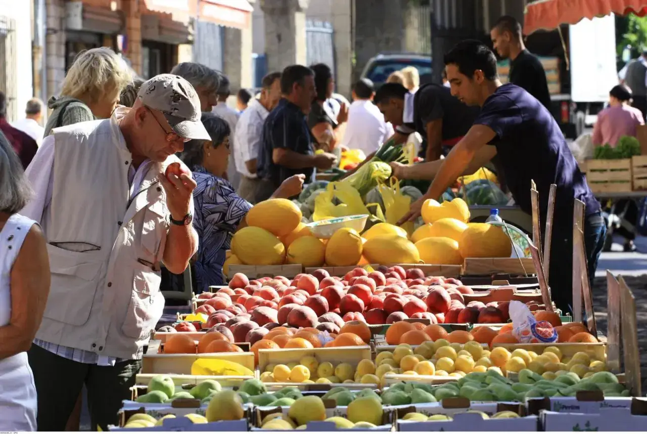 Un homme choisit des fruits sur un &eacute;tal color&eacute; au march&eacute; de Pernes-les-Fontaines. P&ecirc;ches, melons et agrumes abondent.
