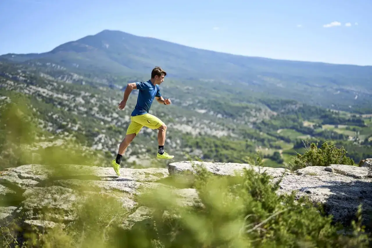 Un coureur en plein effort sur un sentier rocailleux, avec le majestueux Mont Ventoux en toile de fond. L'esprit xrace ventoux incarn&eacute;.
