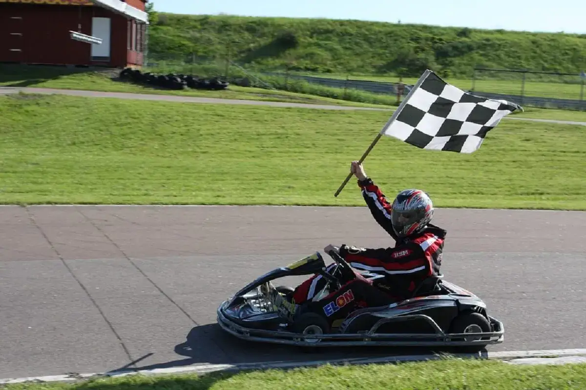 Pilote en karting Vaucluse agite le drapeau &agrave; damier, c&eacute;l&eacute;brant sa victoire sur la piste.