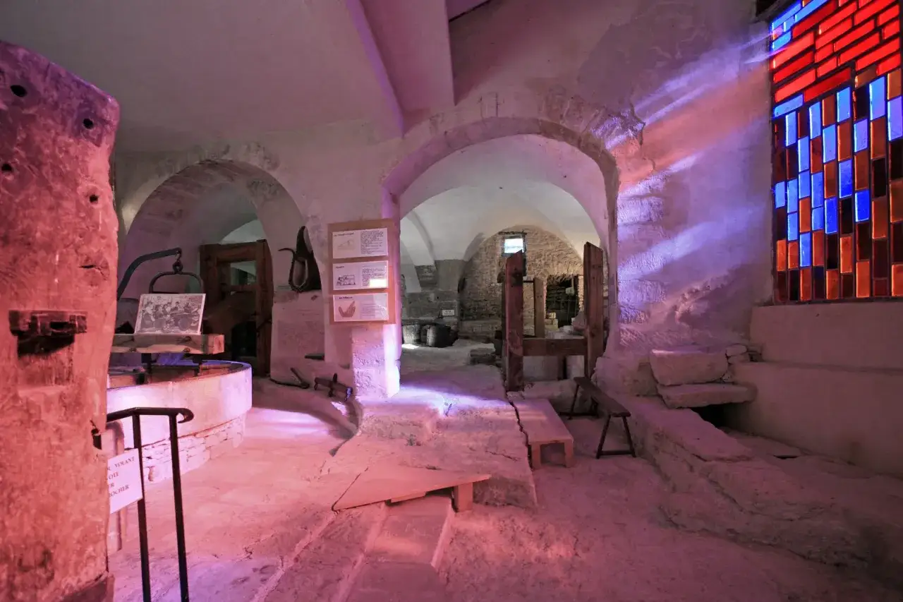 Int&eacute;rieur du mus&eacute;e du vitrail &agrave; Gordes, avec des arches en pierre, un vitrail color&eacute; et des expositions sur l'histoire du verre.