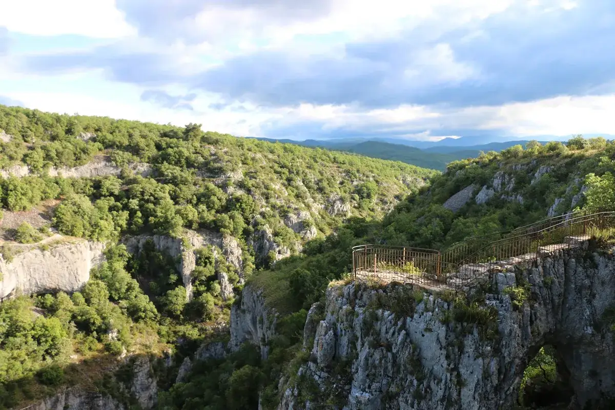 Vue panoramique sur le Calavon, un canyon verdoyant avec une arche rocheuse et un belv&eacute;d&egrave;re.