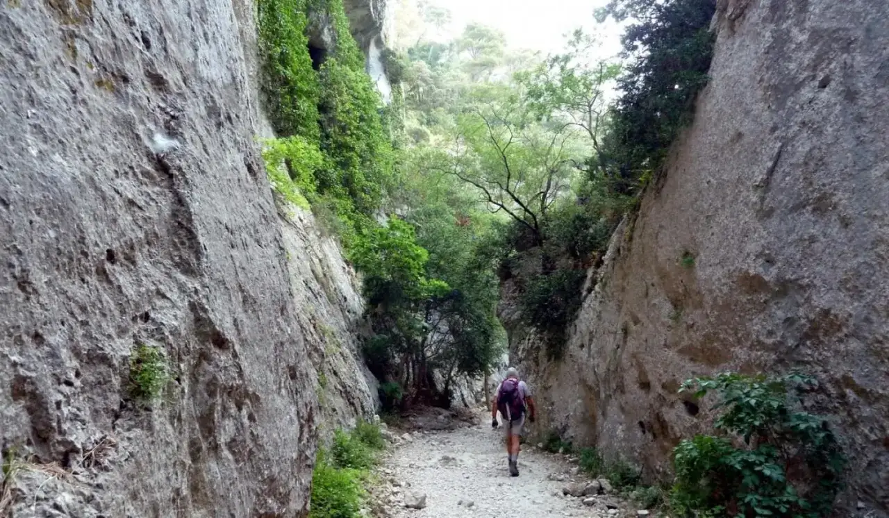 Un randonneur explore les impressionnantes gorges du Régalon, un sentier rocailleux bordé de falaises abruptes et de végétation luxuriante.