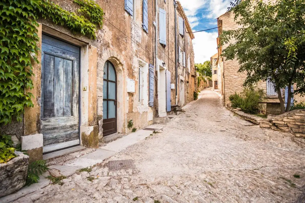 Une ruelle pavée serpente à travers un village perché. Des maisons anciennes aux façades patinées bordent la route des villages perchés.