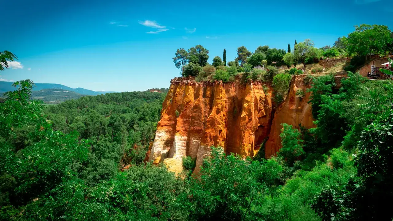 Les Ocres du Roussillon, un site spectaculaire pour savoir que visiter dans le Luberon. Paysage de falaises color&eacute;es et de v&eacute;g&eacute;tation luxuriante.