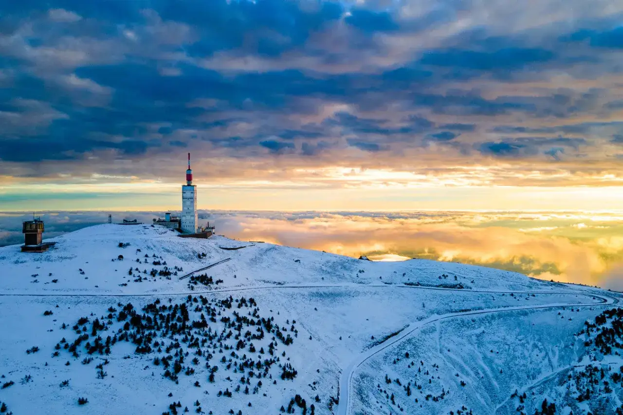 Vue a&eacute;rienne du Mont Ventoux sous la neige, avec ses antennes et un ciel dramatique au coucher du soleil.