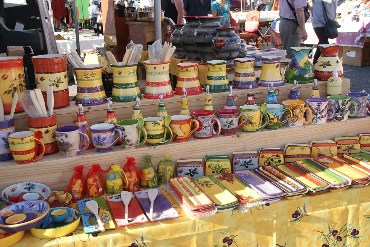 Pots, mugs et vaisselle color&eacute;s, d&eacute;cor&eacute;s d'olives et de lavande, expos&eacute;s sur un &eacute;tal de march&eacute; &agrave; Manosque.