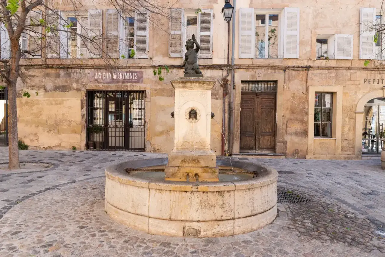 Fontaine et fa&ccedil;ade d'immeuble &agrave; Aix-en-Provence. Id&eacute;al pour visiter Aix-en-Provence &agrave; pied.