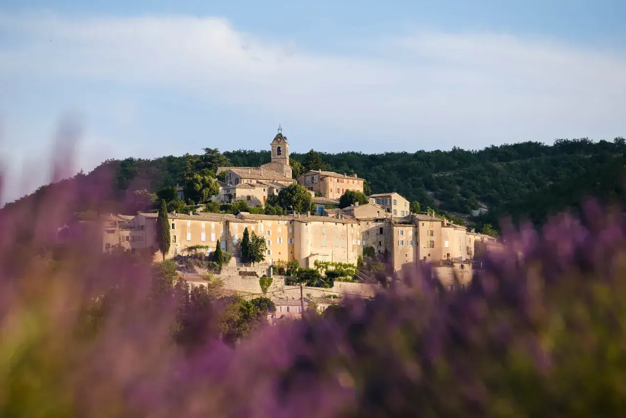 Village perch&eacute; baign&eacute; de soleil, avec son clocher, entour&eacute; de verdure. Un des plus beaux villages autour de Cassis, avec des champs de lavande au premier plan.