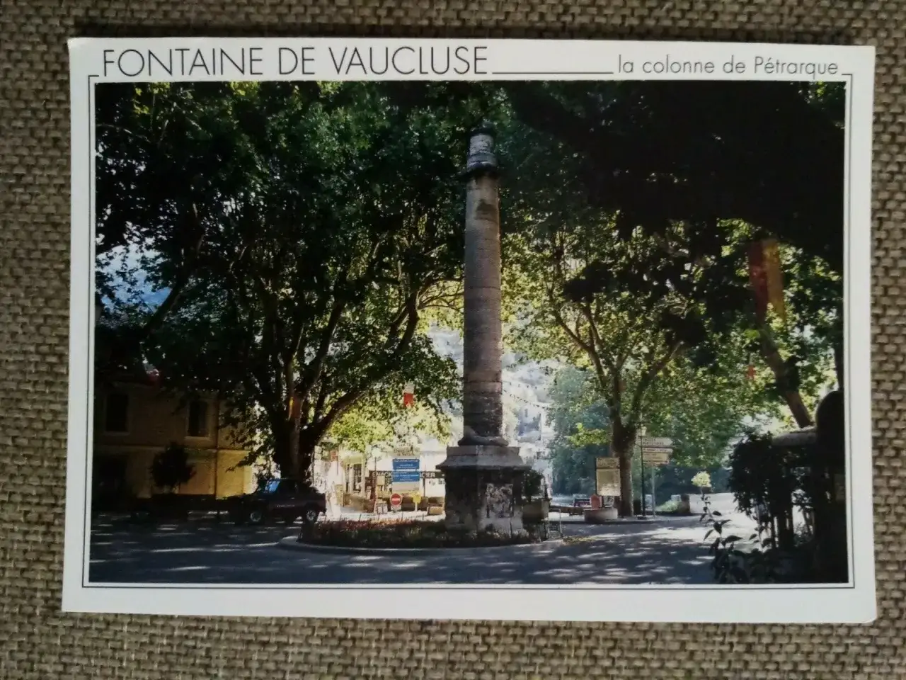 La colonne fontaine de Vaucluse, monument imposant au c&oelig;ur d'un village ombrag&eacute; par de grands arbres.