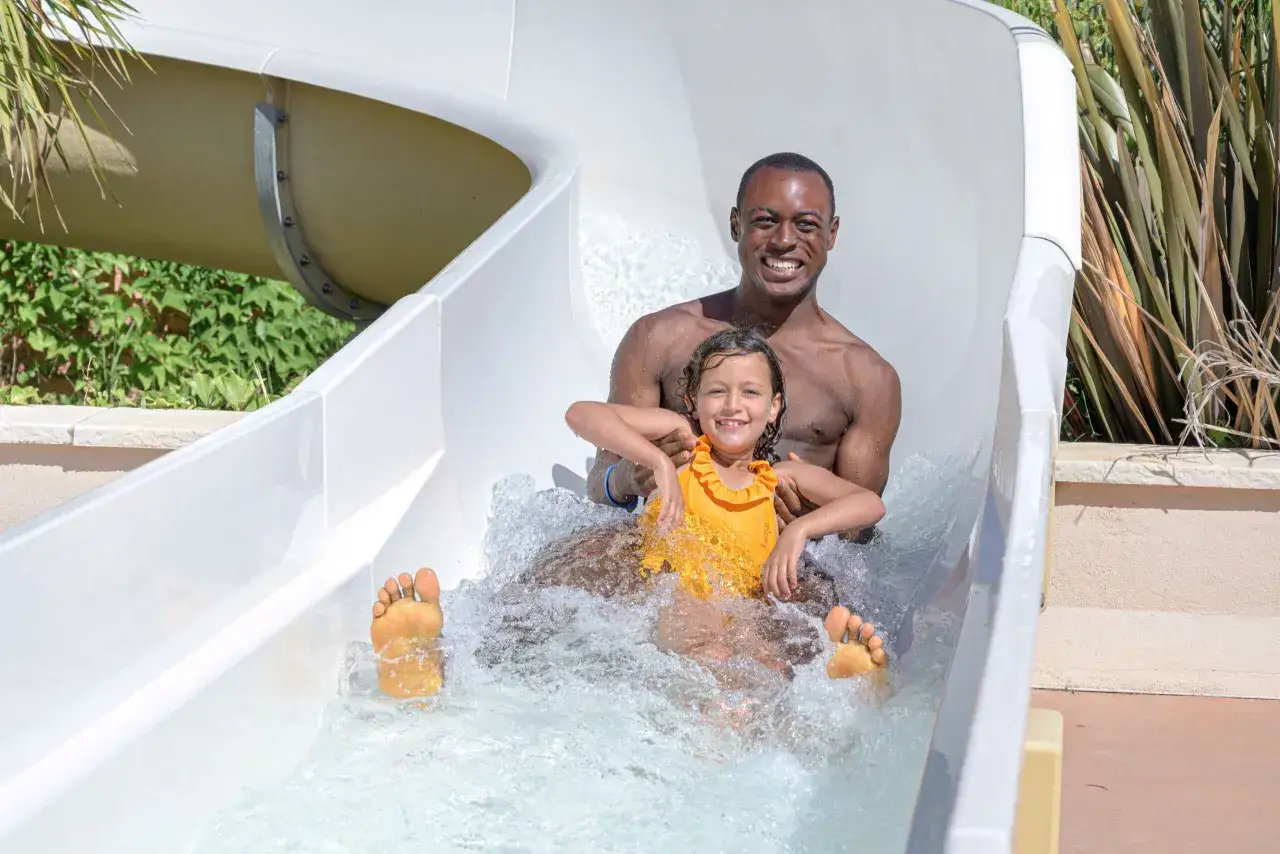 Un p&egrave;re et sa fille rient en d&eacute;valant un toboggan dans un parc aquatique du Vaucluse.