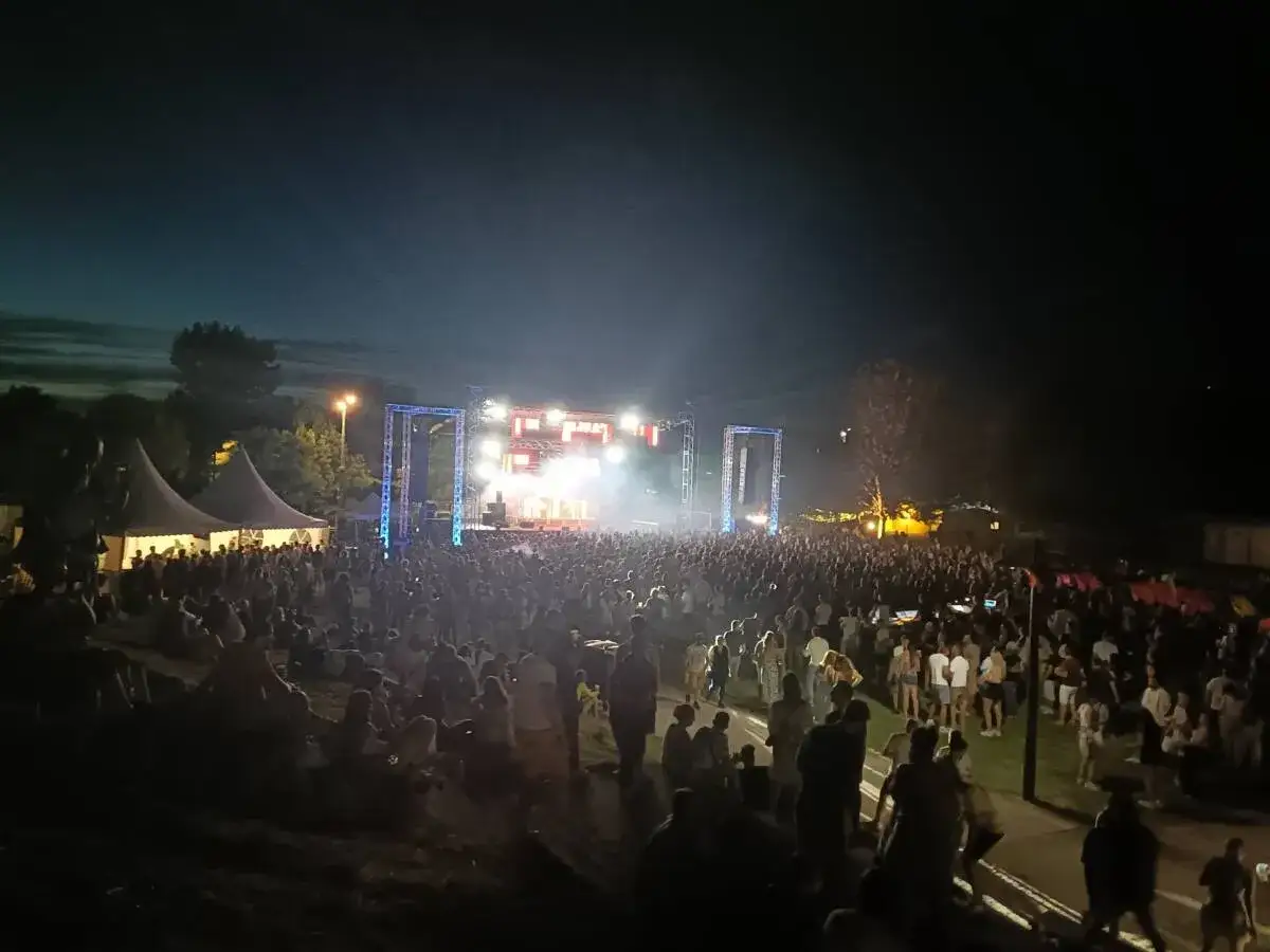 Une foule immense profite de la musique et de l'ambiance lumineuse du festival de Monteux, sous un ciel nocturne.
