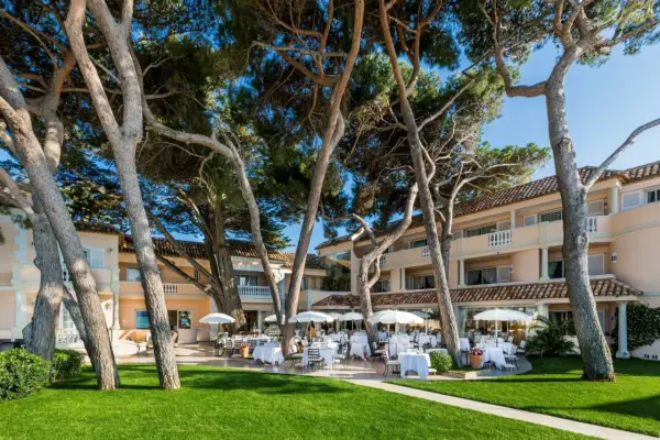 Un magnifique cheval blanc se promène dans un jardin luxuriant en Provence, près d'un hôtel de luxe avec terrasse.