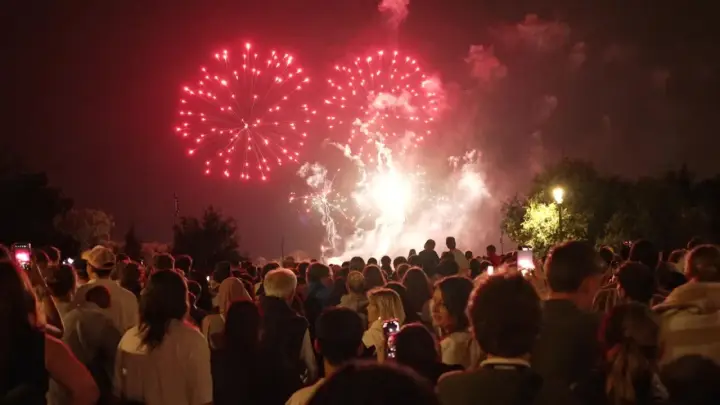Foule admirant un magnifique feu d'artifice rouge au-dessus de la nuit, un spectacle mémorable à Lourmarin.